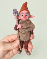 Albin — held in hand for scale, soft pale sage background
